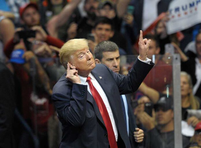 Man in suit gesturing at a crowded event.