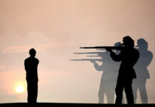 Silhouette of soldiers firing squadding a person