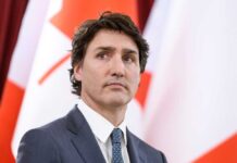 Canadian Prime Minister Justin Trudeau in suit with red and white flags