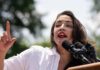 Alexandria Ocasio-Cortez speaking at an outdoor event.