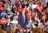Man in front of rally crowd smiling at camera.
