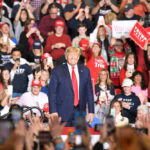 Man in front of rally crowd smiling at camera.