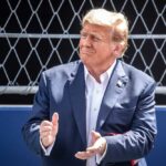 Donald Trump clapping, wearing suit.