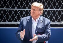 Donald Trump clapping, wearing suit.