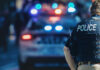 Police officer and vehicle with flashing lights.