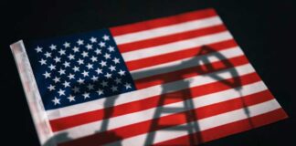 American flag with oil pump shadow overlay.