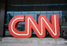Red CNN logo in front of glass building.