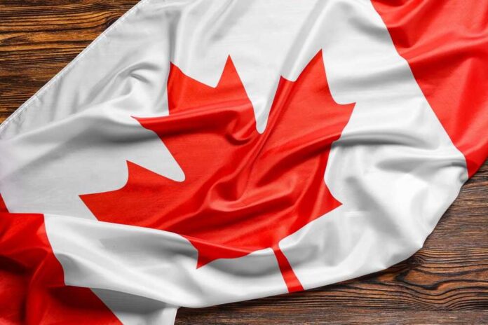 shutterstock_2475176543.jpg featured image Canadian flag with red maple leaf displayed