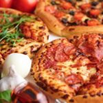 Three pizzas with various toppings and fresh ingredients.