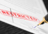 Document labeled restricted with pen signing signature line