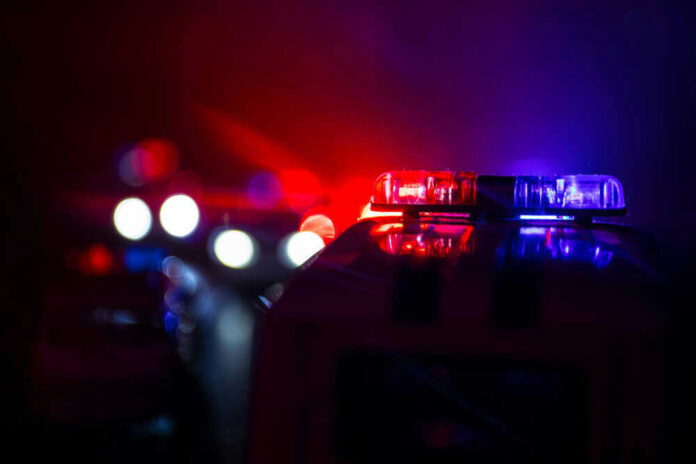 shutterstock_1191163906.jpg Police car lights shining in the dark