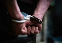 Close-up of hands in handcuffs behind back