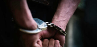 Close-up of hands in handcuffs behind back