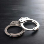 Metal handcuffs on a dark textured surface