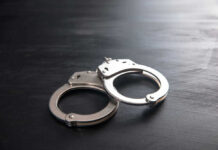 Metal handcuffs on a dark textured surface