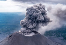 Volcano erupting with large ash plume in sky