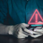 Person holding phone with warning symbol displayed