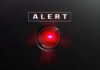 Red alert light against black background text ALERT