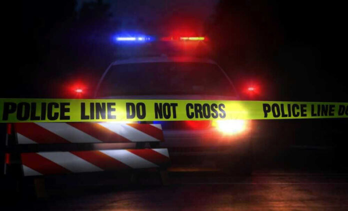 Police car with flashing lights behind caution tape