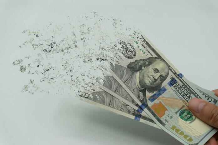 shutterstock_2122253927.jpg Hundred dollar bills disintegrating in hand