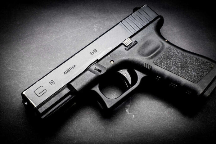 shutterstock_463051378.jpg Black Glock 19 pistol on a dark surface