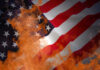 American flag partially set on fire with orange flames