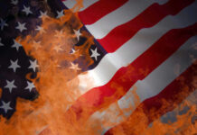 American flag partially set on fire with orange flames
