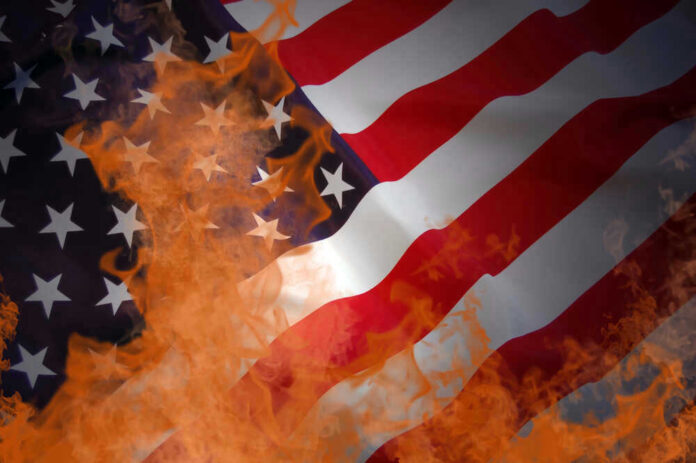 shutterstock_47429077.jpg American flag partially set on fire with orange flames