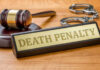 Gavel handcuffs and death penalty sign on table