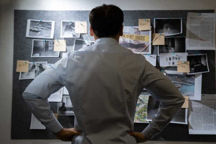 Man examining investigation board with photos and notes