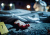 Crime scene with covered body and hand exposed