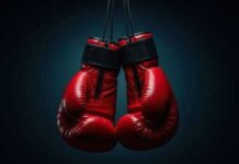 A pair of red boxing gloves hanging against a dark background