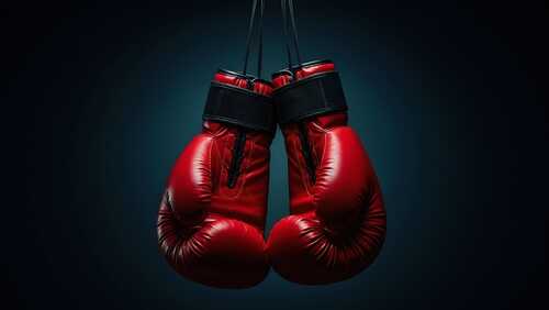 A pair of red boxing gloves hanging against a dark background