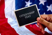 Hand holding a card that reads CITIZENSHIP TEST in front of an American flag