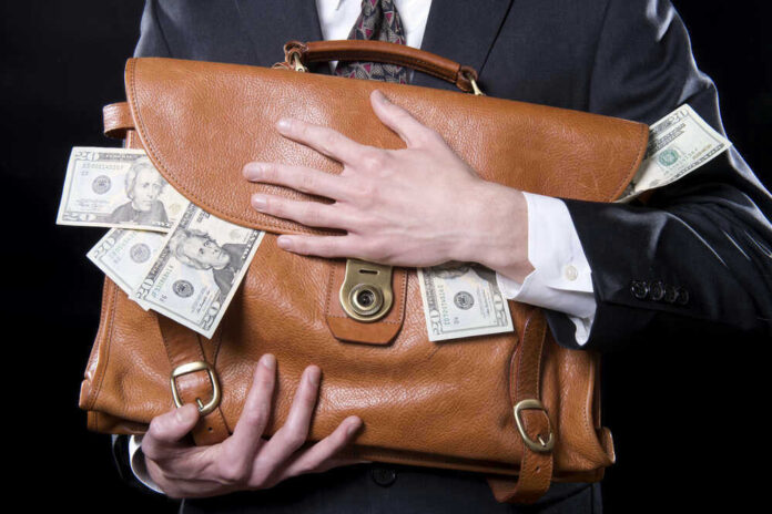 shutterstock_133129220.jpg Person holding briefcase with money protruding from it