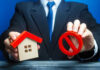 Businessman holding house model and prohibition sign