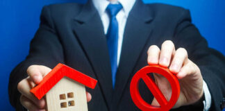 Businessman holding house model and prohibition sign