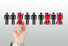 Hand crossing out stick figures with a red marker.