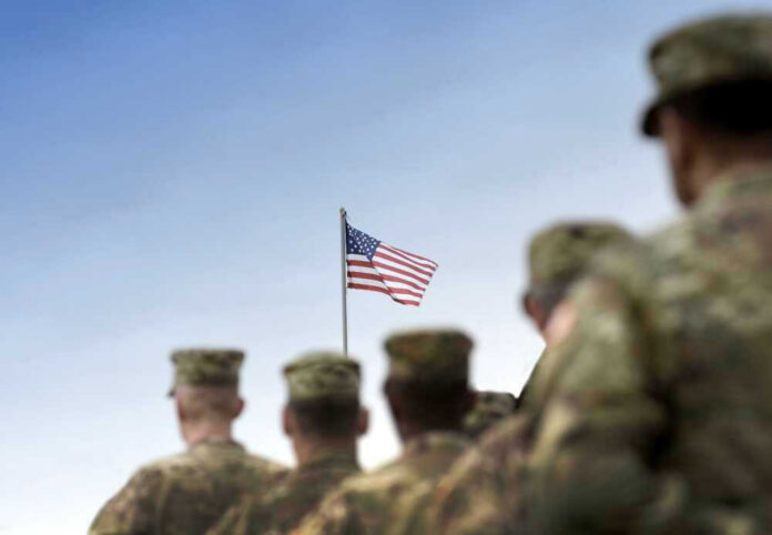 shutterstock_2380883205-1.jpg Soldiers in uniform with American flag in background