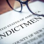 Close-up of an indictment document with glasses resting on it