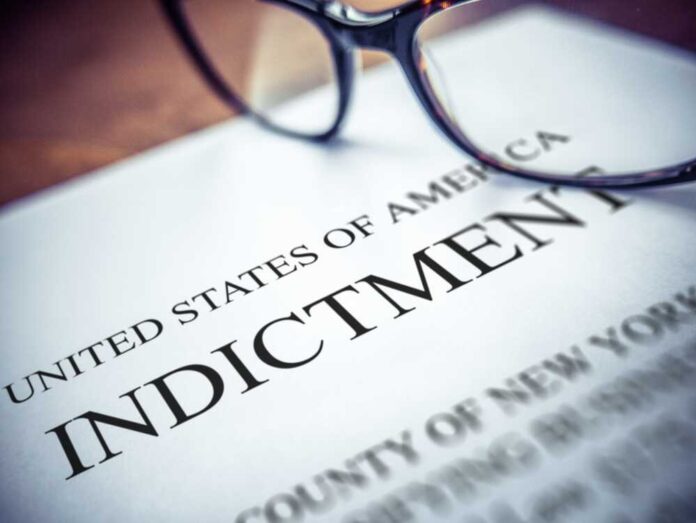 shutterstock_2470639133.jpg Close-up of an indictment document with glasses resting on it