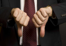 Two hands showing thumbs down in a suit.