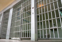 Empty prison cell with metal bars and toilet.