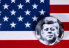A black and white badge of John F. Kennedy on an American flag background