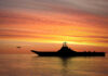 Silhouette of an aircraft carrier at sunset.