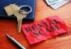 A crumpled red paper labeled 'RENTAL SCAM' next to keys and cash
