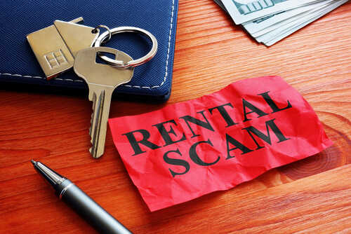 shutterstock_1679294830 (2).jpg A crumpled red paper labeled 'RENTAL SCAM' next to keys and cash