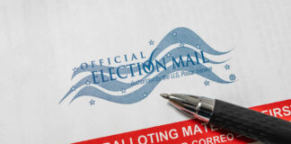 Vote-by-mail envelope with pen on top.