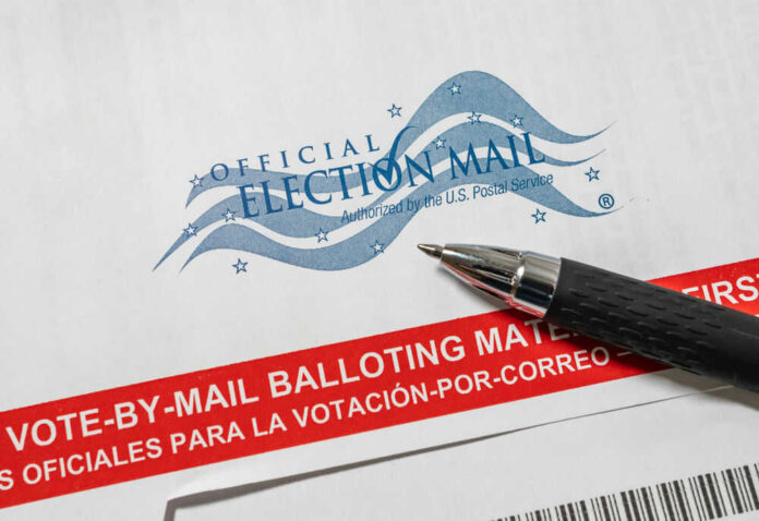 Vote-by-mail envelope with pen on top.