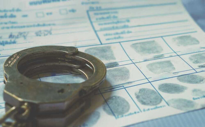 shutterstock_2291869477.jpg Handcuffs on a fingerprint document.